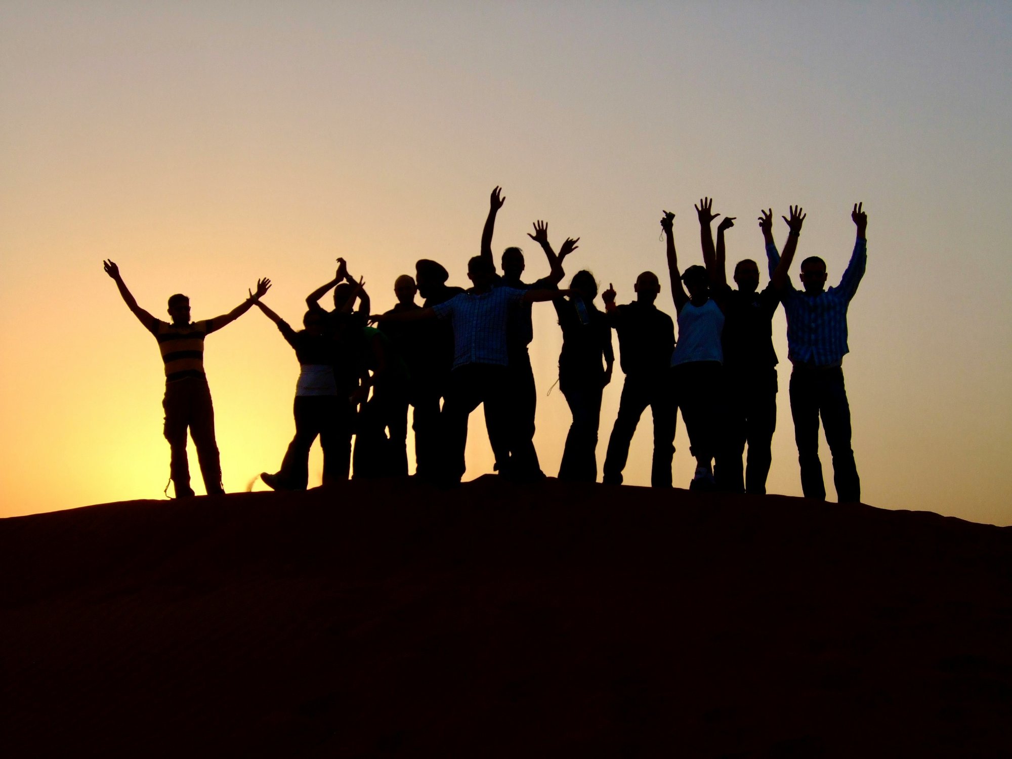 Grupo de personas celebrando al atardecer en la cima de una colina tras completar un reto