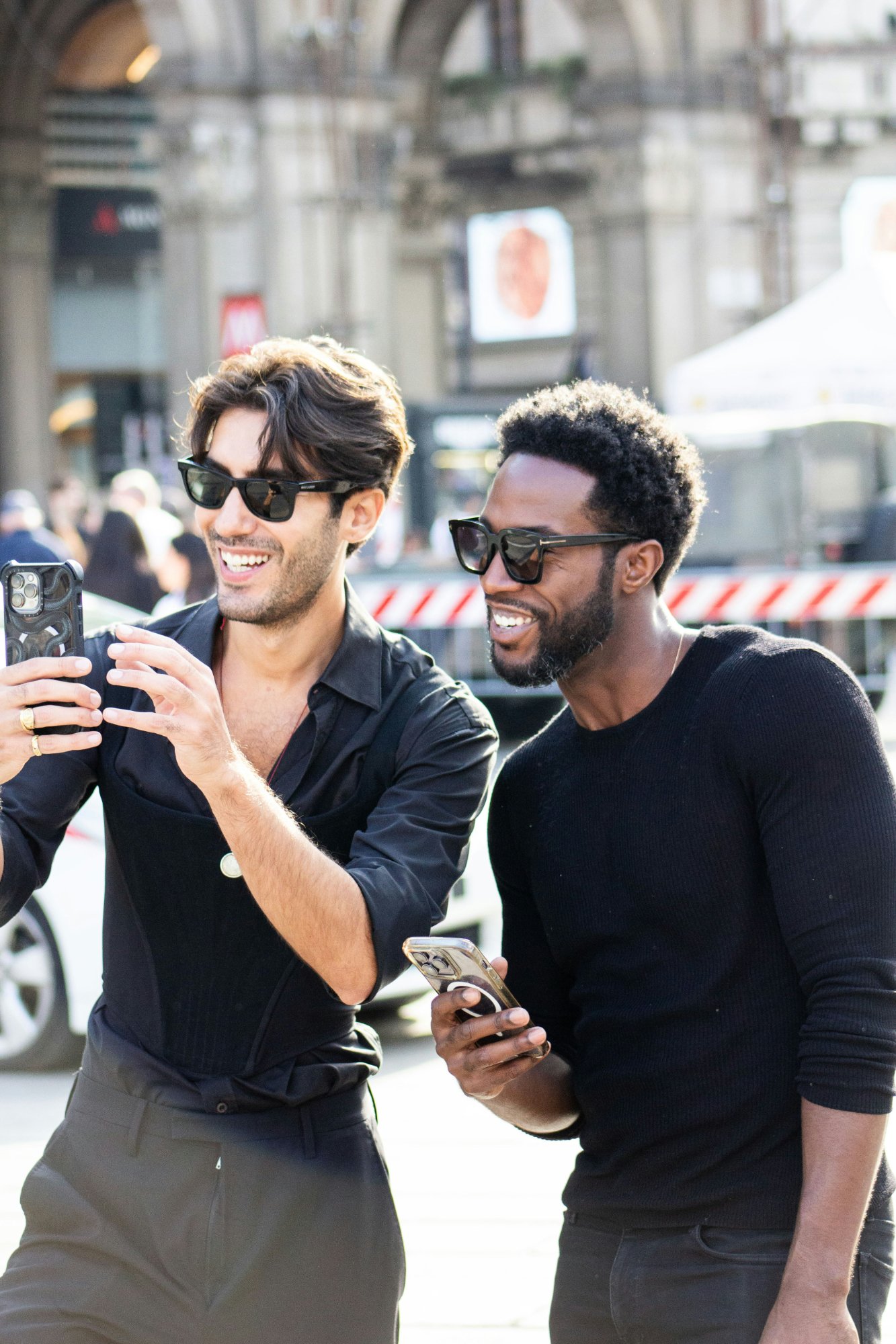Two friends enjoying a mini-game on their phone while walking through the city