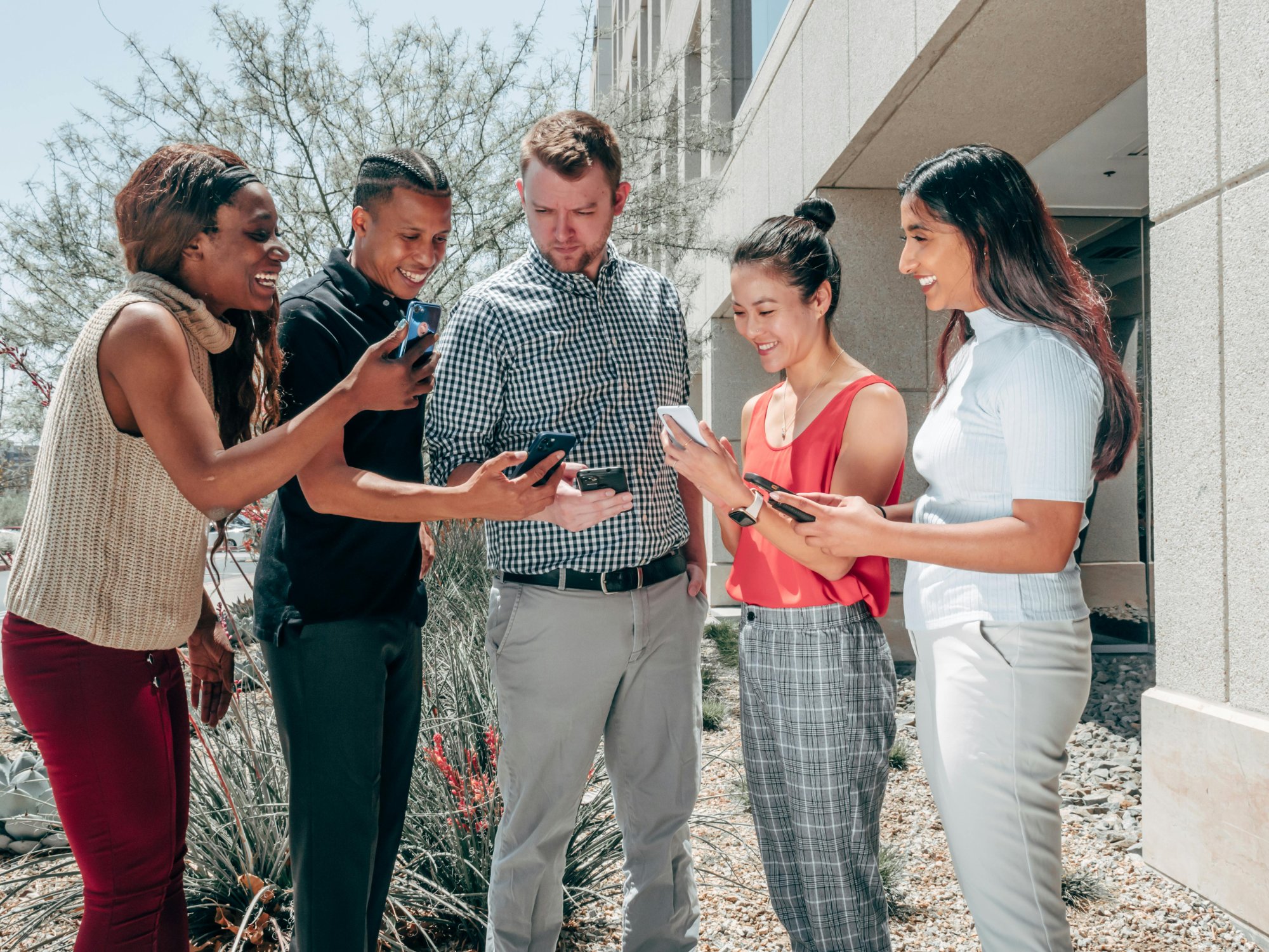 Groupe diversifié de collègues interagissant avec leurs téléphones lors d'un teambuilding à distance